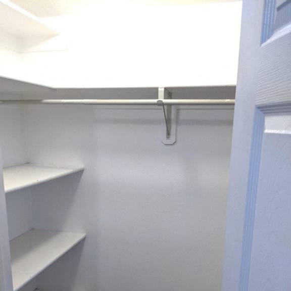 a white closet with shelves and a door.