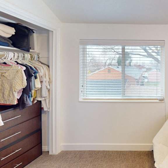 a white chair sits in a room with a window and a plant.