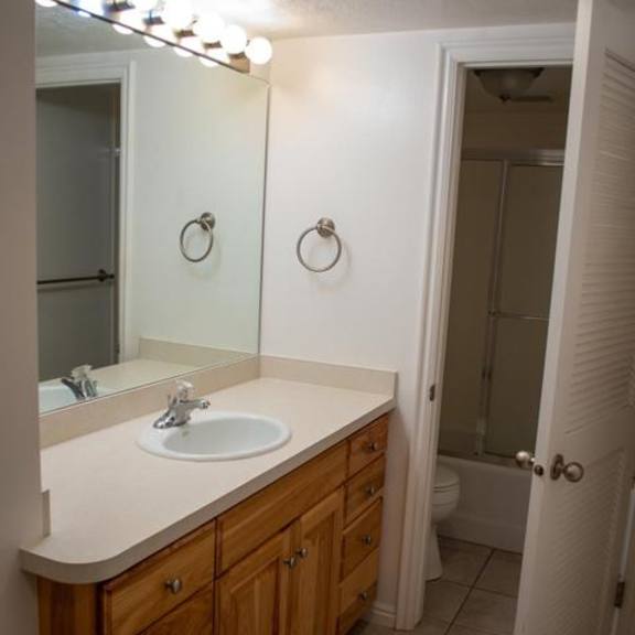 a bathroom with a sink, mirror, and lighting fixture.