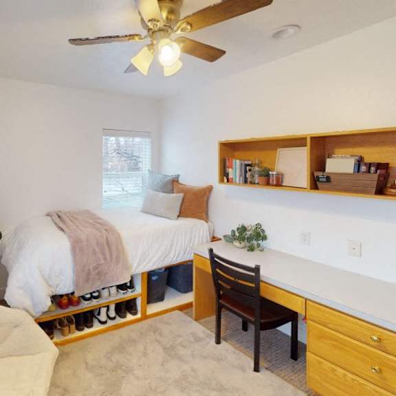 a bedroom with a bed, chair, and a ceiling fan.