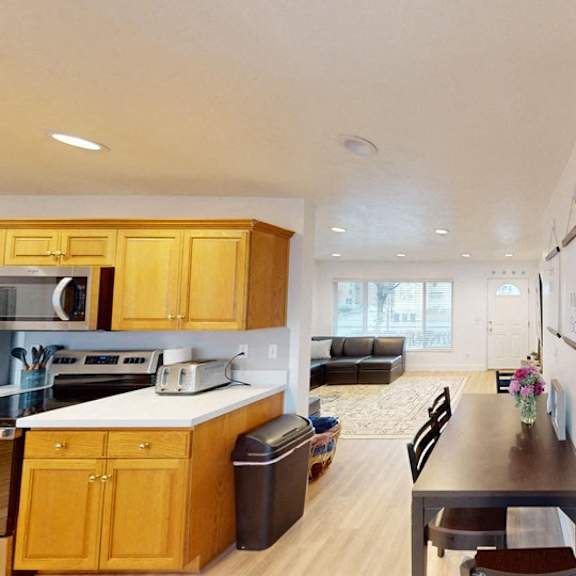 a kitchen with wooden cabinets and a black trash can.
