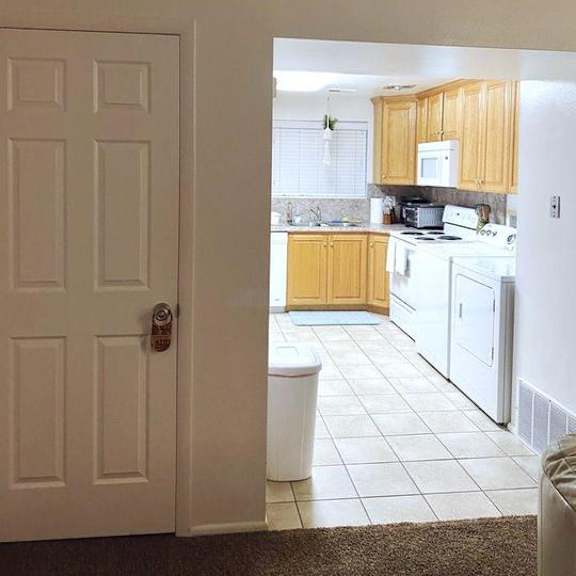 a white door is open to a kitchen.