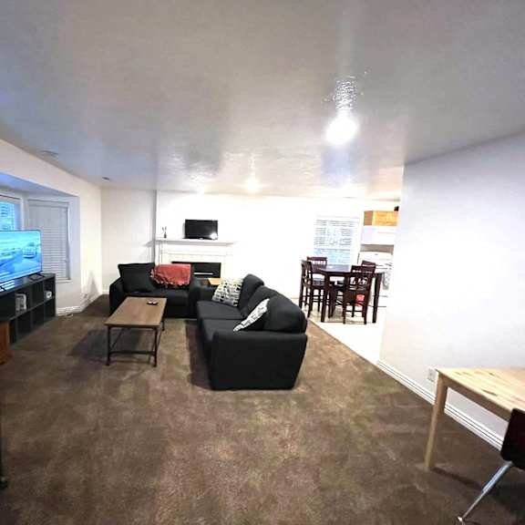 a living room with a black couch, a television, and a wooden coffee table.