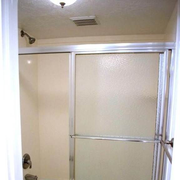 a white bathroom with a toilet and a walk in shower.