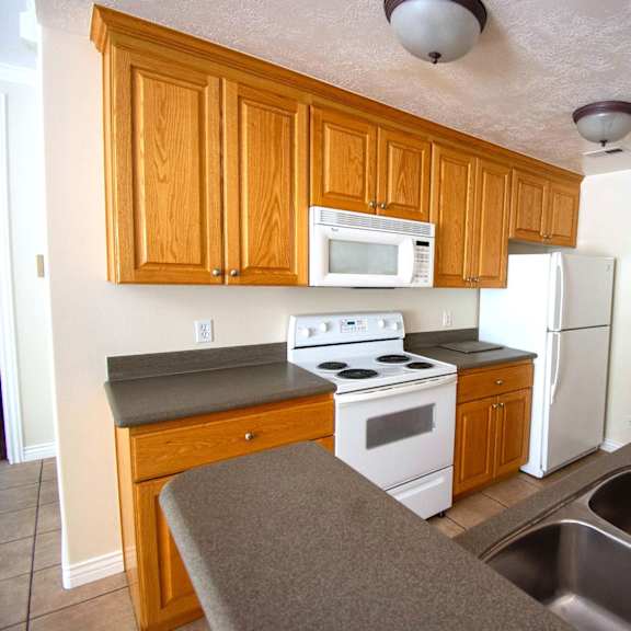 a kitchen with a stove, microwave, refrigerator, and sink.