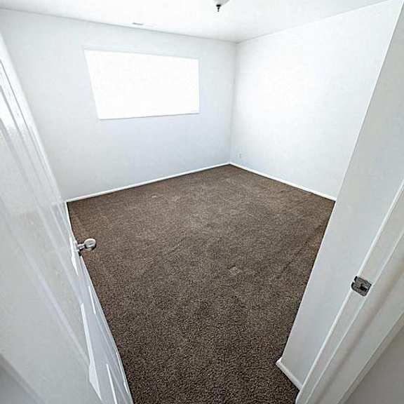 a carpeted room with a door and a window.