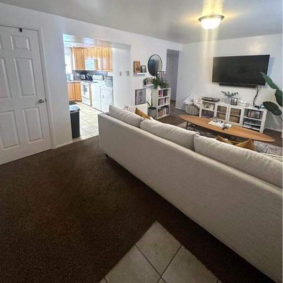 a living room with a white couch and a flat screen tv mounted on the wall.