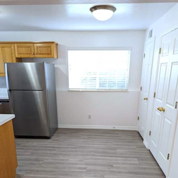 a kitchen with a refrigerator, wooden cabinets, and a white door.