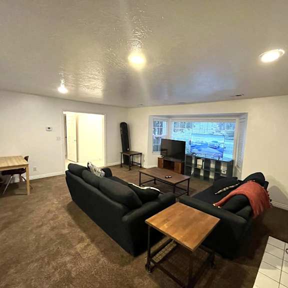 a living room with a black couch and a television on the wall.