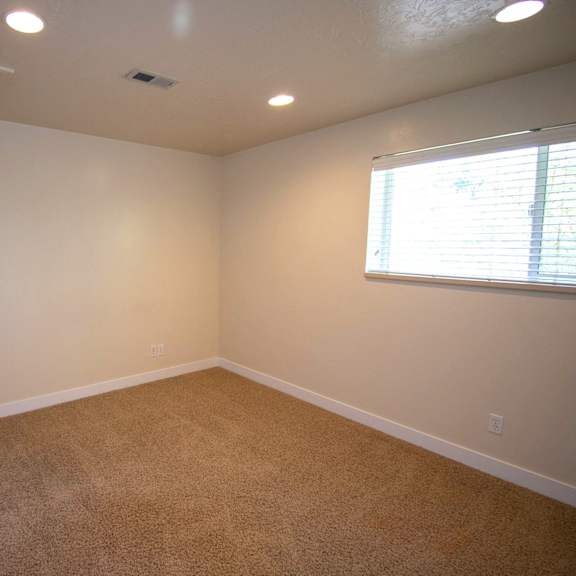 a room with a carpeted floor and a window with blinds.