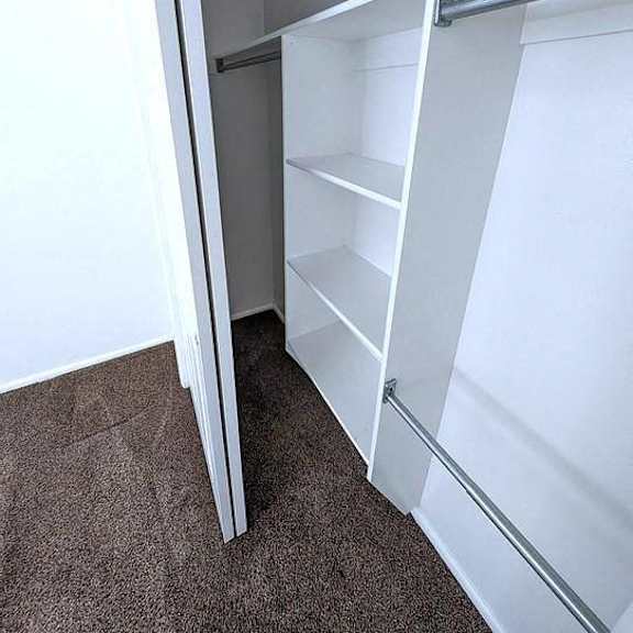 a white closet with shelves and a rod for hanging clothes.