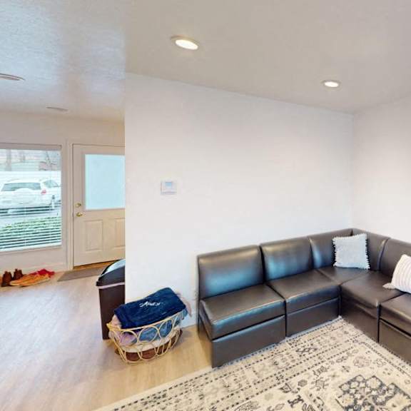 a black leather couch with a white pillow and a basket on the floor.