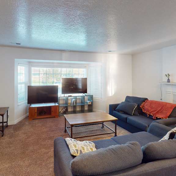 a living room with a grey couch and a fireplace.