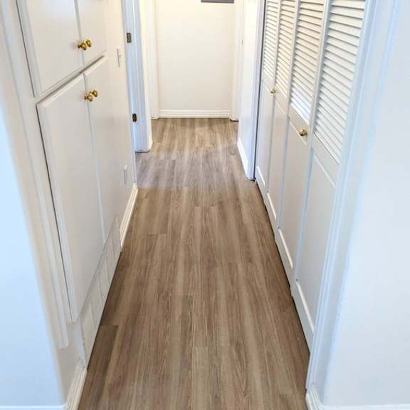 a hallway with white doors and wooden floors.