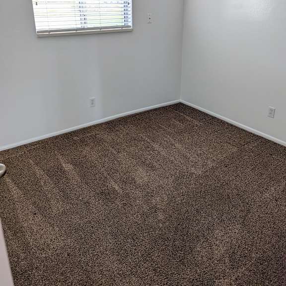 a room with a carpeted floor and a window with blinds.