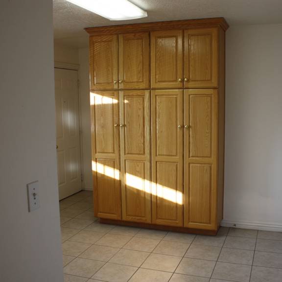 a wooden cabinet with four doors is in a room with white walls.