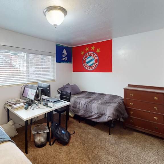 a room with a bed, desk, and a bayern munich flag.