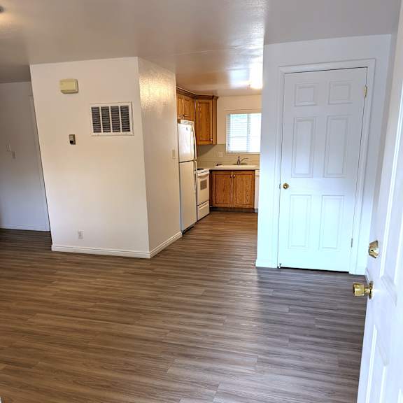 a kitchen with a white door and wooden floors.