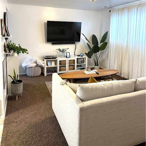 a living room with a white couch and a flat screen tv mounted on the wall.