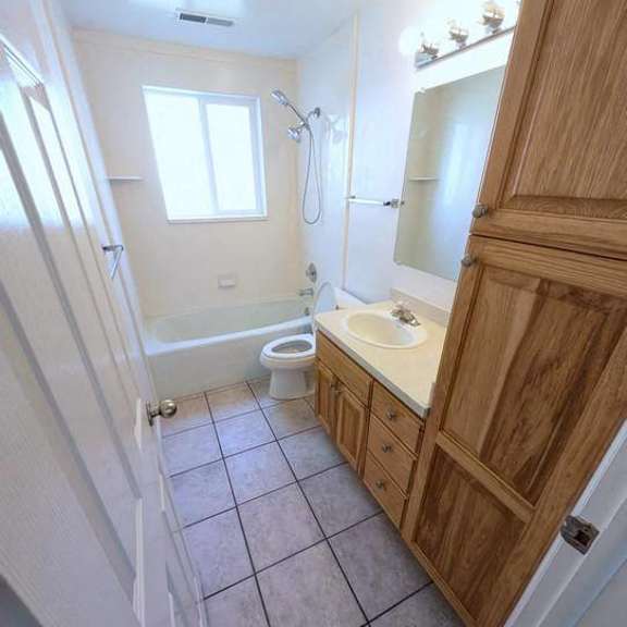a bathroom with a toilet, sink, and mirror.