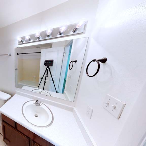 a white bathroom with a toilet, sink, and mirror.