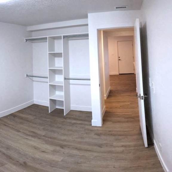 an empty room with white walls and wood flooring