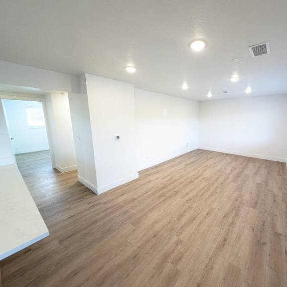 an empty living room with wood floors and white walls