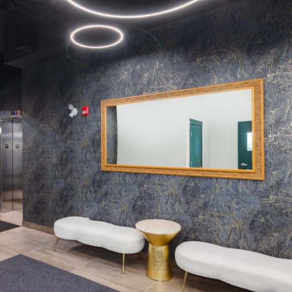 a hallway with a bench, a mirror, and a rug.
