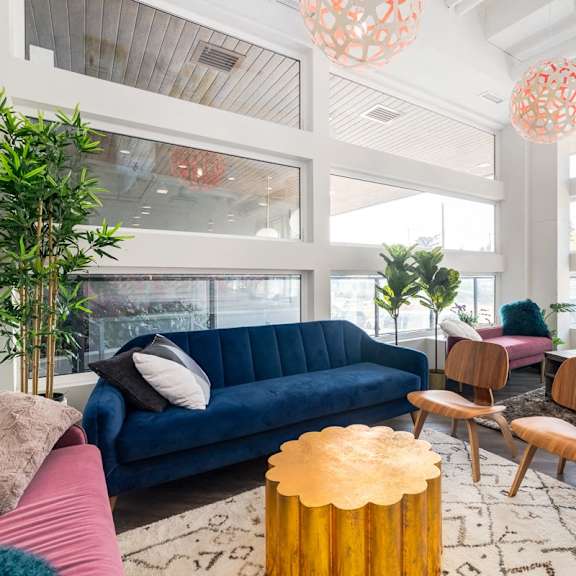 a living room with a blue couch and wooden chairs.