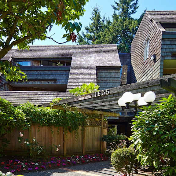 a house with a wooden fence and bushes in front of it