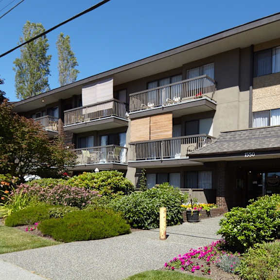 a large apartment building with balconies and a garden in front of it