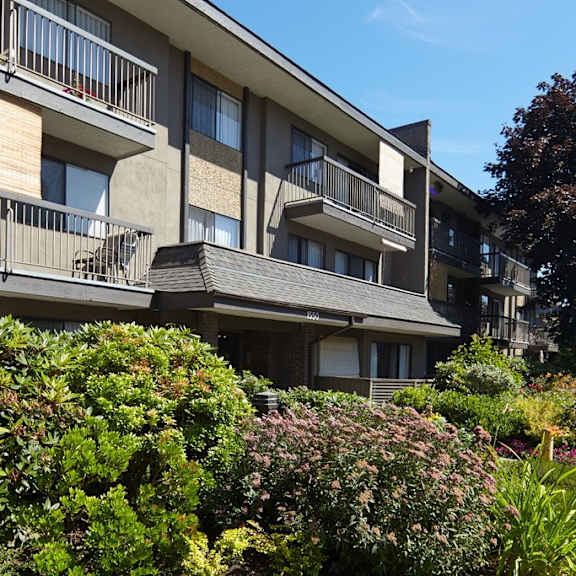 a large apartment building with balconies and a garden in front of it