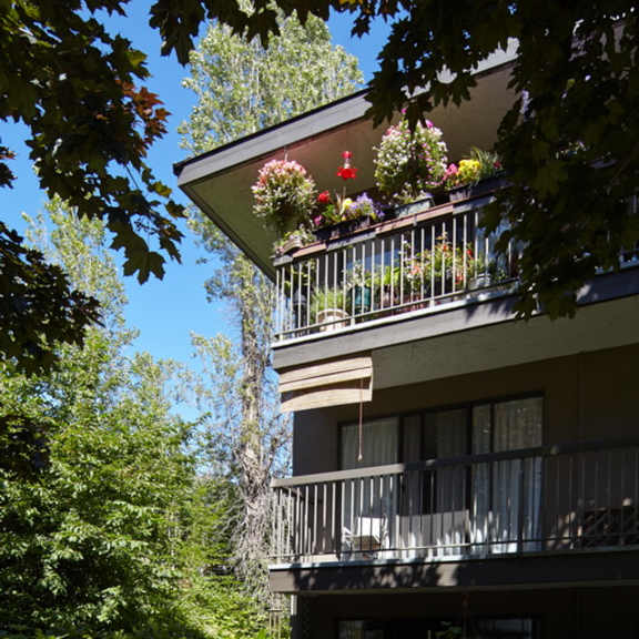 an apartment building with a balcony full of flowers