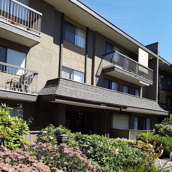 an apartment building with balconies and a tree in the background
