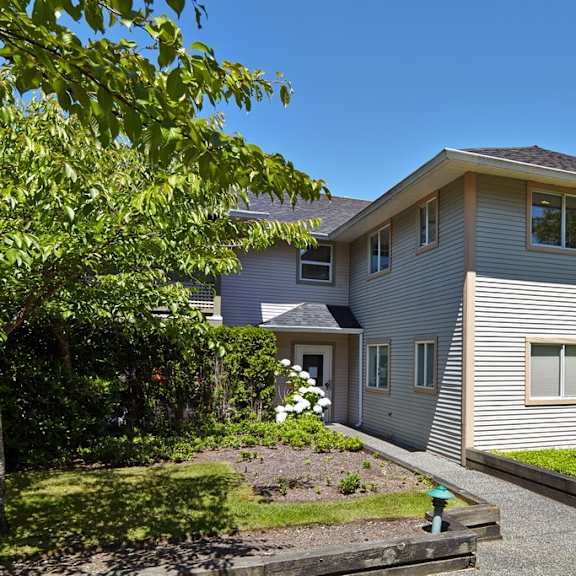 a house with a gray siding and a green lawn