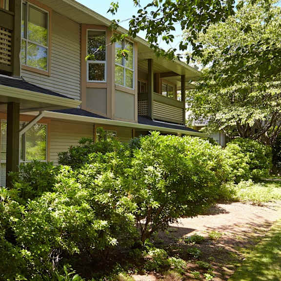 a walkway in front of a house with trees in the background