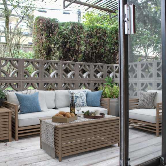 a patio with wooden furniture and a wooden fence in the background