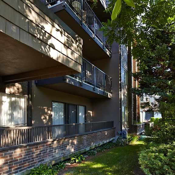 an apartment building with balconies and a large tree in front of it