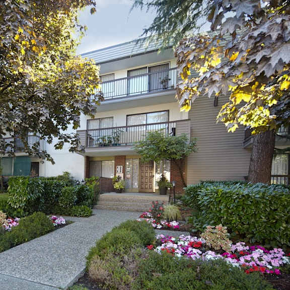 a picture of an apartment complex with a walkway in the middle of a grassy area