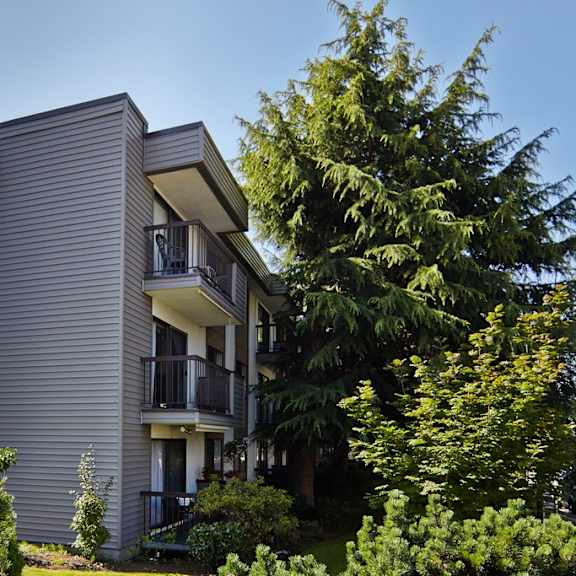 a picture of a gray apartment building with a blue sky in the background