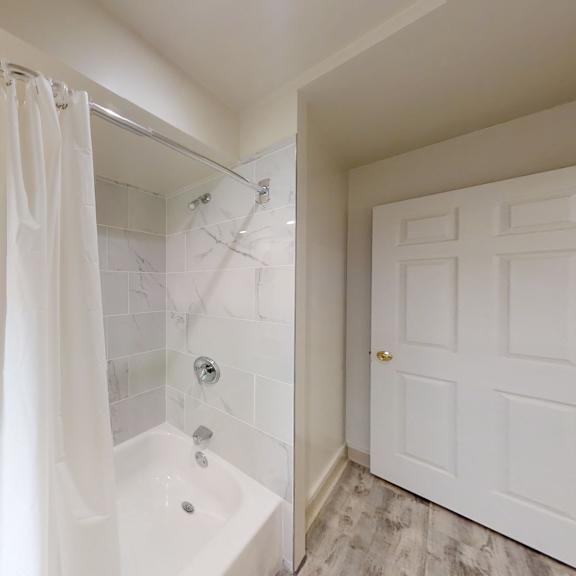 a white bathroom with a tub, shower, and a window.