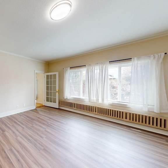 a room with wooden floors and a window with white curtains.