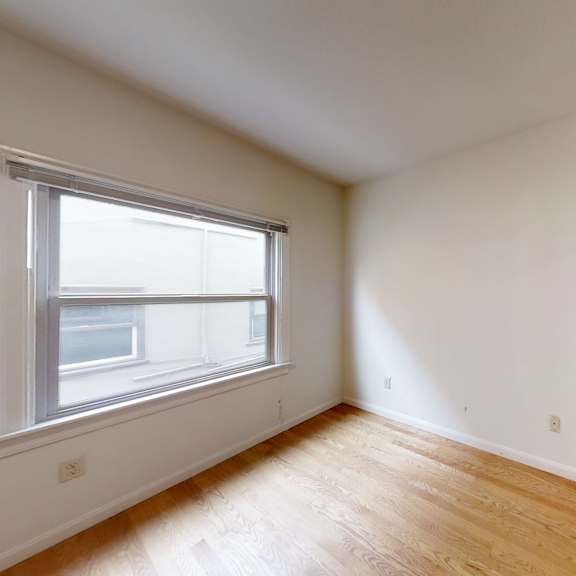 a room with a window and wooden flooring.