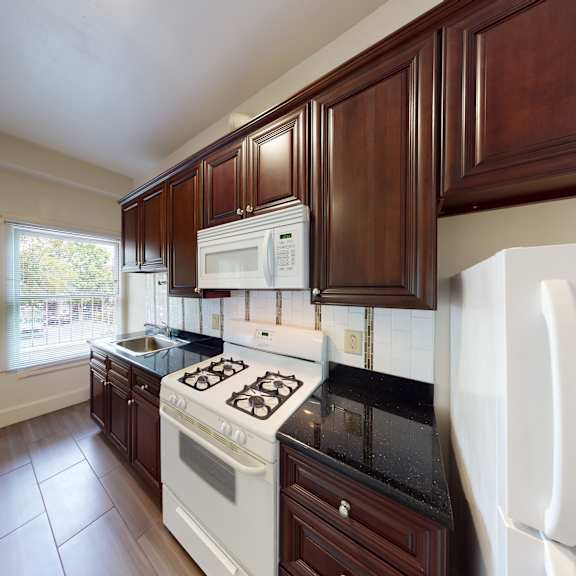 a kitchen with white appliances and dark wood cabinets.