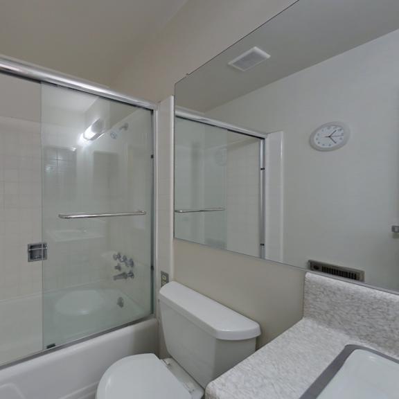 a white bathroom with a glass shower door and a toilet.