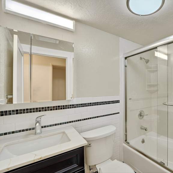 a white bathroom with a sink, toilet, and shower.