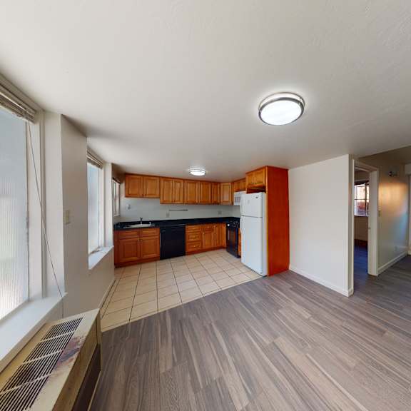 a spacious kitchen with wooden floors and white walls.
