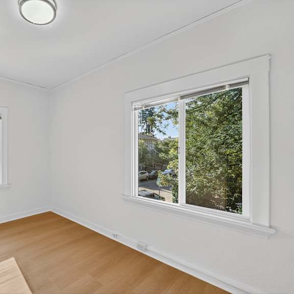 a room with a window showing a view of a street and trees.