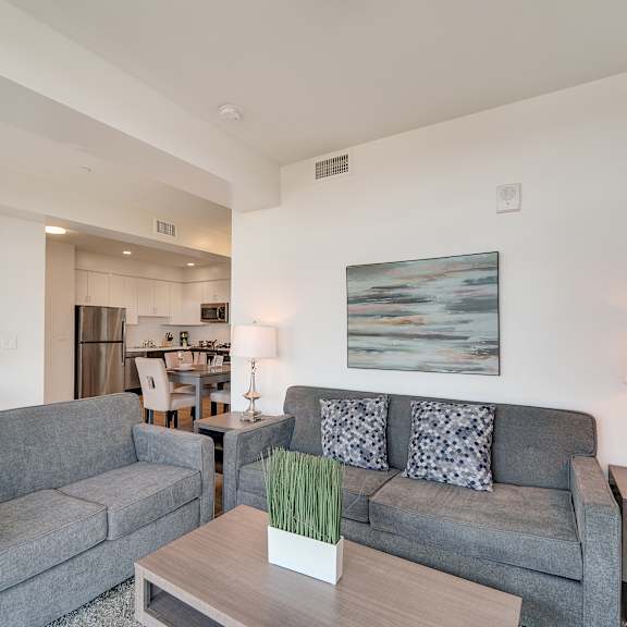 a living room with a grey couch and a painting on the wall.