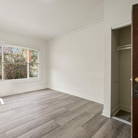 a room with a large window and wooden flooring.